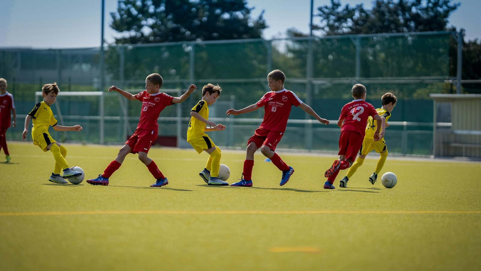 Players in a grassroots football match on a grass pitch
